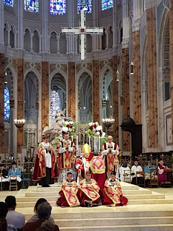 Die Aufnahme von Altar und Chorraum zeigt den Kardinal, der auf dem Thronsessel seine Predigt verliest, umgeben von weiteren zum Teil auf den Stufen des Altares sitzenden Mitgliedern des Altardienstes.